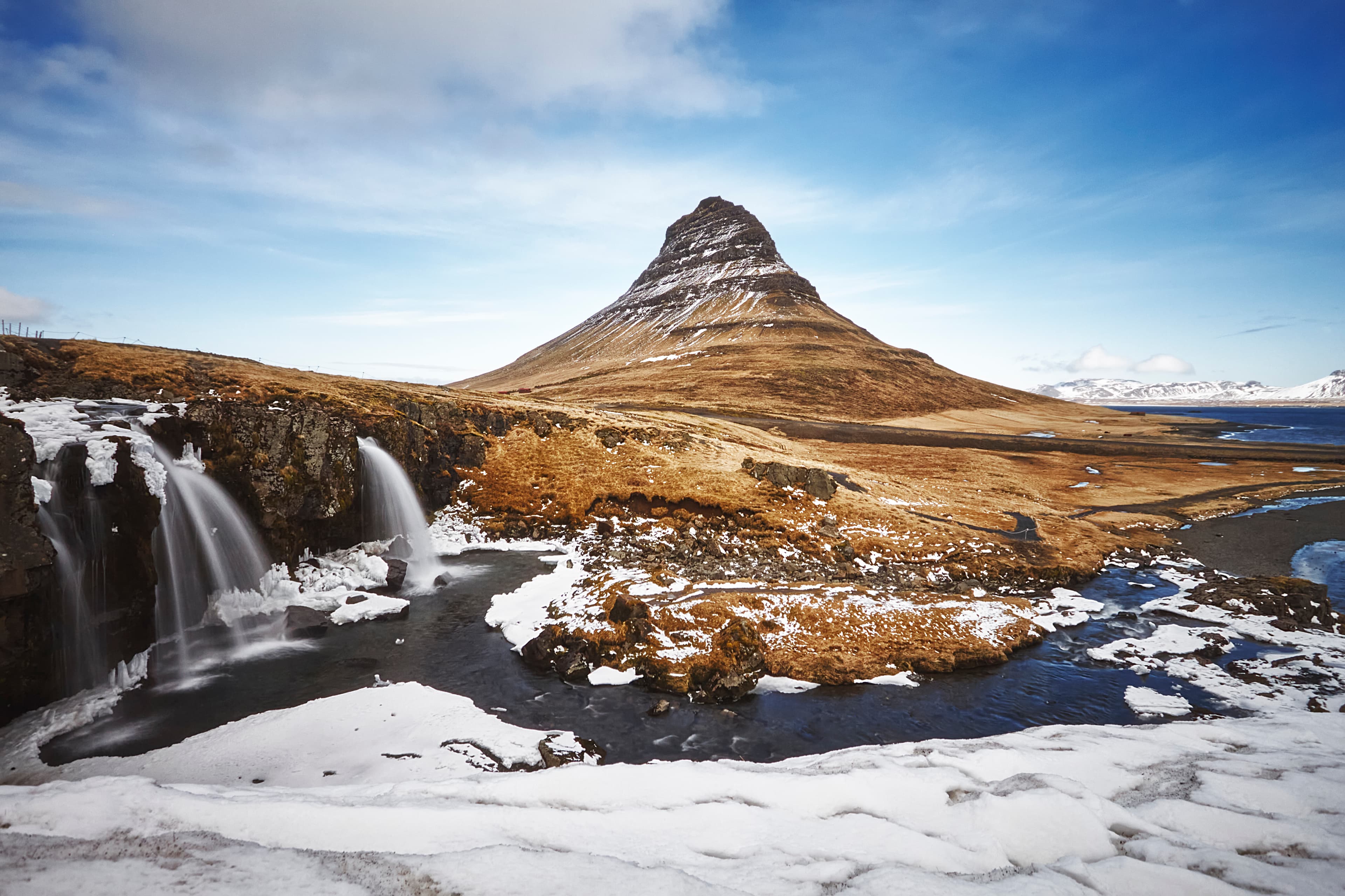 Monte Kirkjufell en primavera con vegetación verde y cielo despejado, Islandia